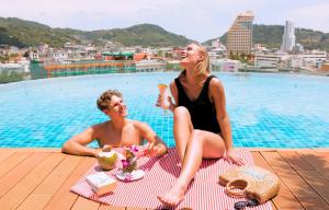 パトンビーチにあるThe Marina Phuket Hotelのプール横の毛布に腰掛けた男女