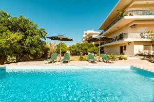 a swimming pool with chairs and umbrellas next to a building at Chania Dream House in Chania