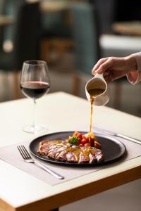 a person pouring sauce on a plate of food with a glass of wine at The Marina Phuket Hotel in Patong Beach