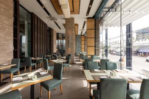 a restaurant with wooden tables and green chairs at The Marina Phuket Hotel in Patong Beach