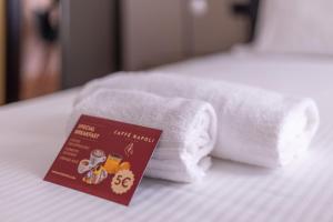 einen Haufen Handtücher auf einem Bett mit einem Buch in der Unterkunft Lupetta 3 in Mailand