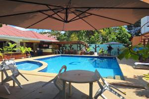a pool with a table and chairs and an umbrella at Citadel Bed and Breakfast in Puerto Princesa City