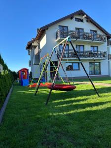 a playground in the grass in front of a house at Komfort i spokój blisko natury - Apartamenty i pokoje ARKO in Ostrowo
