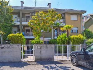 an apartment building with a white fence and a tree at Villetta Giulietta-casa con giardino e parcheggio in Grado
