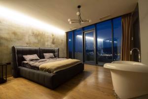 a bedroom with a bed and a tub and a large window at Tbilisi view in Tbilisi City +5 photos
