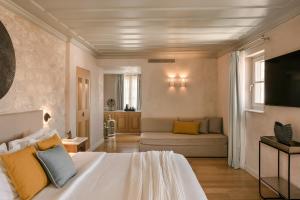 una camera da letto con un letto bianco e un divano di Hydroussa Hotel Hydra a Hydra