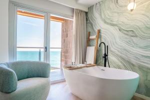 a bathroom with a tub and a chair and a window at INNSiDE by Meliá Alicante Porta Maris in Alicante