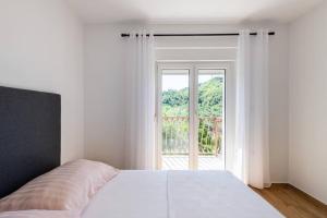 a white bedroom with a bed and a large window at Villa La Domazet in Podstrana