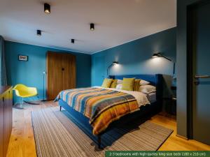 莱赫阿尔贝格Appart Hotel Knappaboda的一间有蓝色墙壁的卧室和一张带黄色枕头的床