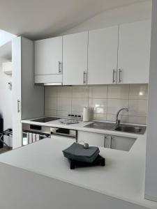 a kitchen with white cabinets and a sink and a counter at Apartment J.J in Požarevac