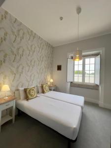 a bedroom with a large white bed and a window at Thomar House in Tomar