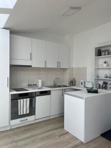 a white kitchen with white cabinets and appliances at Apartment J.J in Požarevac