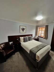 a bedroom with a large bed and a chair at The Stag Hotel in Banchory