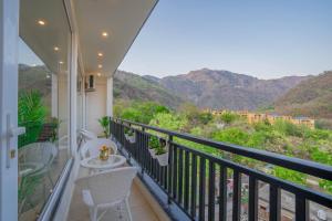 Un balcón con mesa y sillas y montañas. en Perfectstayz Value Alpine Retreat, en Rishīkesh