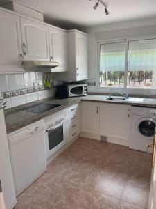 a kitchen with white cabinets and white appliances at Casa Verano in Alicante