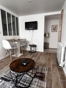 a living room with a table and a television at Logement proche gare et Versailles in Marly-le-Roi