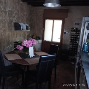 a dining room table with a vase of flowers on it at Les chambres du vieux quartier in Thouars +19 photos