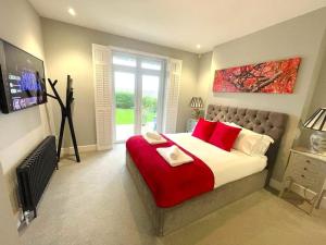 a bedroom with a large bed with red pillows at Thorndale - Luxury Coastal Home - Hot Tub , Cinema & Games Room in Westward Ho
