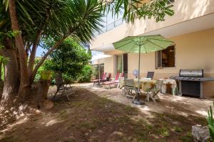 a patio with a table and a green umbrella at Appartement dans cadre de verdure in La Seyne-sur-Mer