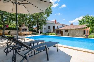 a swimming pool with two tables and an umbrella at Casa Ana Tripari by Briskva in Višnjan