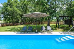 a group of chairs and an umbrella next to a pool at Casa Ana Tripari by Briskva in Višnjan
