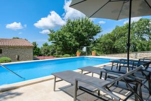 a swimming pool with chairs and an umbrella at Casa Ana Tripari by Briskva in Višnjan