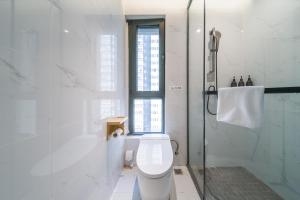 a white bathroom with a toilet and a shower at Jianguo Puyin Hotel - Xi'an Big Wild Goose Pagoda University of Science and Technology Qujiang Campus Metro Station in Xi'an +19 photos