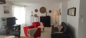 ein Wohnzimmer mit einem Sofa und roten Stühlen in der Unterkunft Chez Camille appartement spacieux 75m2 climatisation wifi parking terrasse et cour privative a 50 m de la plage in Le Grau-du-Roi