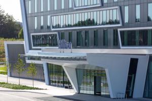 a building with two chairs in front of it at Hilton Aberdeen TECA in Aberdeen