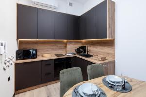 une cuisine avec des armoires noires et une table avec des chaises dans l'établissement Resort Hevenia Mrzeżyno - Apartament 1, à Mrzeżyno 6 autres photos