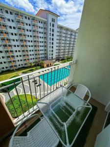 una mesa y sillas en un balcón con piscina en Field Residences -1 bedroom Comfort Inn, en Manila