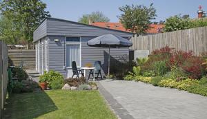 einen kleinen Garten mit einem Tisch und einem Sonnenschirm in der Unterkunft Hotelletje de Veerman in Oost-Vlieland
