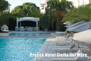 a pool with chairs and umbrellas next to a hotel at Villetta Tina in Vada