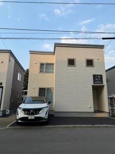 a silver car parked in front of a building at Nomad Stay Chitose in Chitose