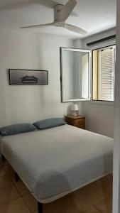 a white bed in a bedroom with a ceiling fan at Céntrico apartamento a 150 metros de la playa. Parking* in Lloret de Mar