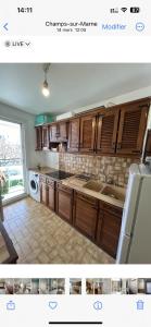 cocina con armarios de madera y electrodomésticos de cocina en Appart 2 ch près RER Champs sur Marne - Disneyland et Paris, en Champs-Sur-Marne