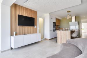 a living room with a television on a wall at Vue mer - Séjour à deux pas de la plage in La Barre-de-Monts