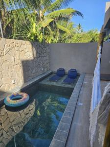 ein Pool mit zwei blauen Stühlen neben einer Wand in der Unterkunft Kanui VK 102 Milagres - Duplex Perto da Capela e Raizeiros in São Miguel dos Milagres