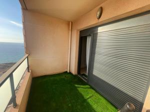 a balcony with a door with green grass on it at Frange Maritime Canastel in Bir el Djir