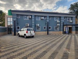 a white car parked in front of a blue building at Duplessis Lodge in Kempton Park