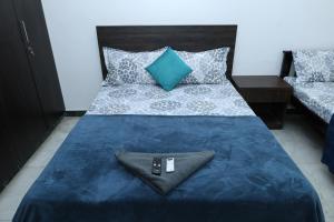 a bed with a blue blanket and a remote control on it at Greams Road Near Apollo Deluxe Fusion Serviced Apartments in Chennai