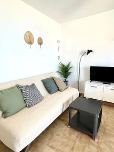 a living room with a white couch and a tv at Apartamento Indalo en primera linea de playa in Las Negras