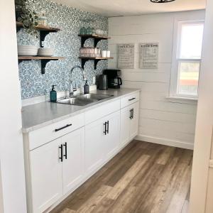 a kitchen with white cabinets and a sink at Magnolia House PEI in Souris +16 photos