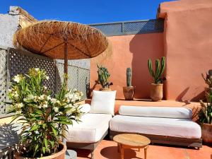 a patio with couches and potted plants and an umbrella at Riad Dar Zouar & Spa in Marrakech