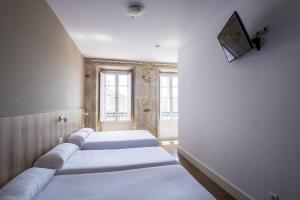 Habitación con 3 camas y TV en la pared. en Hotel Alda Avenida, en Santiago de Compostela