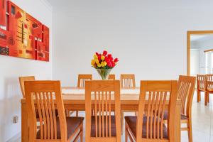 una mesa de comedor con sillas y un jarrón de flores en Apartamento Casa Matilda, en Armação de Pêra