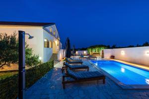 a swimming pool with two lounge chairs next to a house at Villa Gabi in Pridraga