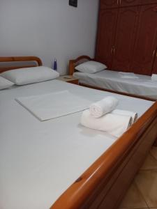 two beds in a room with white sheets and towels at GuestHouseMantho in Gjirokastër +99 photos