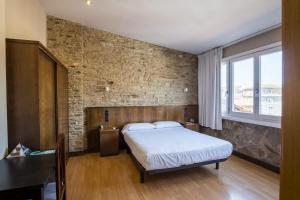 Un dormitorio con una cama y una pared de ladrillo. en Hotel Alda Avenida, en Santiago de Compostela