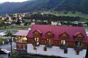 a house with a red roof with a mountain in the background at hotel "Riverside Mestia" in Mestia
